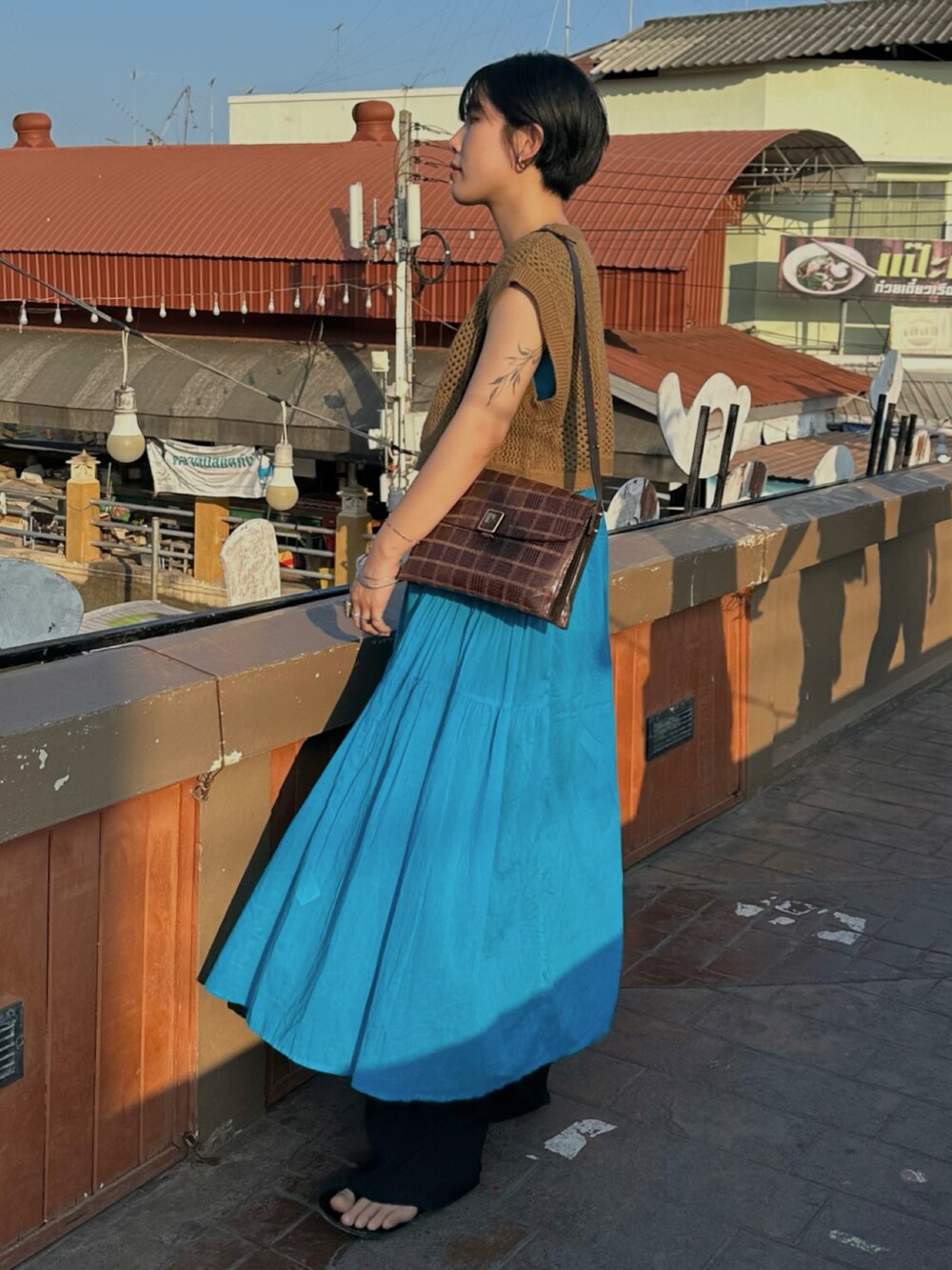 ブルー系のワンピース、ブラウン系のニット/セーターを着用したレディースの春コーディネートの2枚目の写真