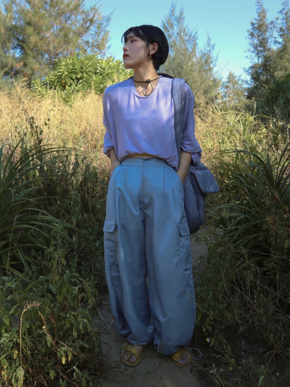 パープル系のトップス、ブルー系のパンツ、イエロー系のサンダルを着用したレディースの夏コーディネートの2枚目の写真