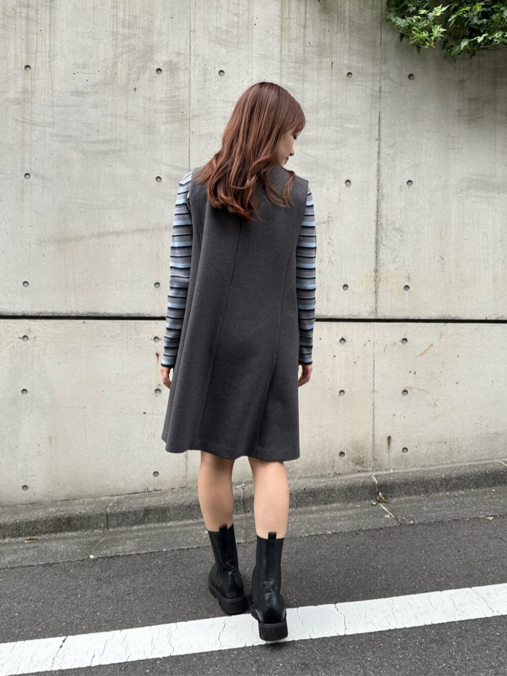 ブラック系のブーツ、グレー系のニット/セーター、グレー系のジャンパースカートを着用したレディースの秋コーディネートの5枚目の写真