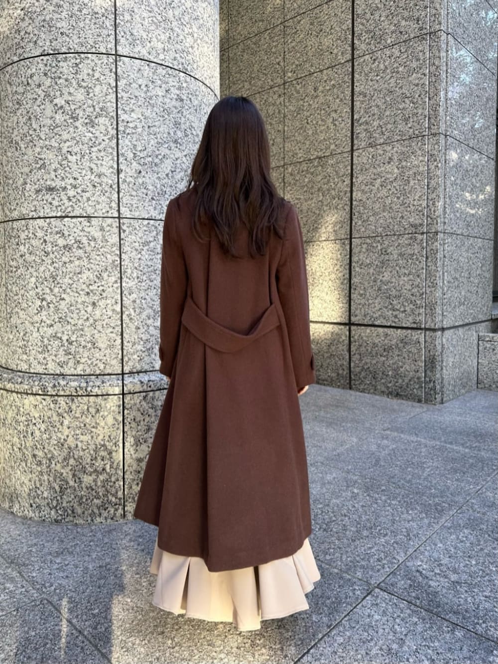 ブラウン系のブーツ、ブラウン系のチェスターコート、ホワイト系のニット/セーターを着用したレディースの冬コーディネートの3枚目の写真