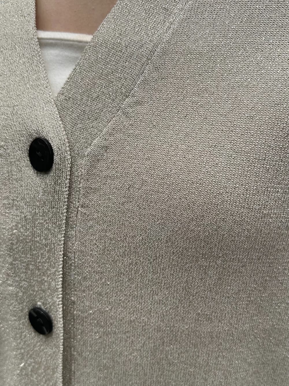 シルバー系のサンダル、ブラック系のボストンバッグ、ホワイト系のベストを着用したレディースの夏コーディネートの5枚目の写真