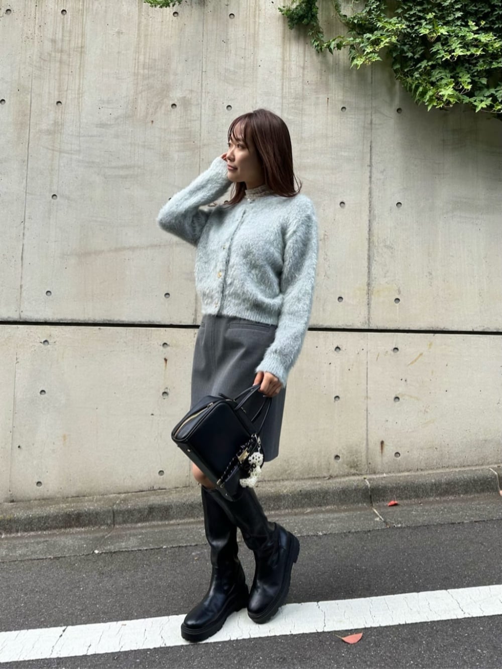 ブラック系のボストンバッグ、ブラック系のブーツ、グリーン系のカーディガン/ボレロを着用したレディースの秋コーディネートの2枚目の写真