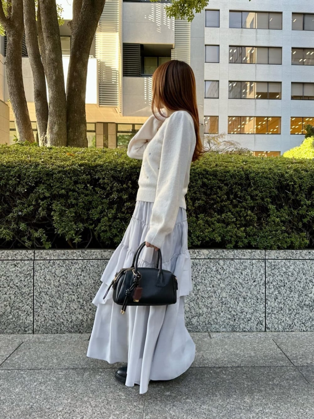 ブラック系のブーツ、ブラック系のボストンバッグ、グレー系のスカートを着用したレディースの冬コーディネートの2枚目の写真