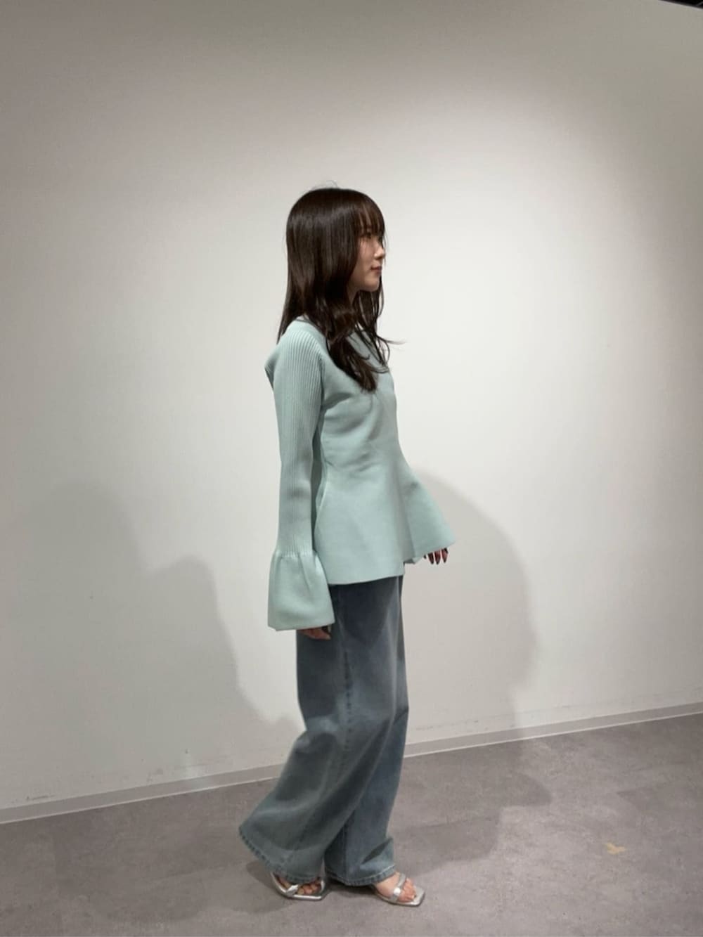 グリーン系のニット/セーター、ブルー系のデニムパンツを着用したレディースの冬コーディネートの2枚目の写真
