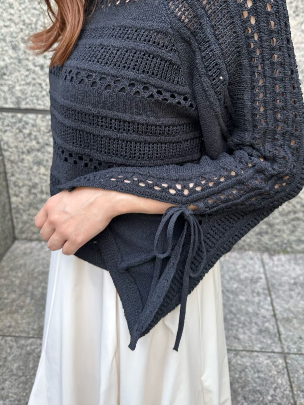 ブラック系のショルダーバッグ、ブラック系のブーツ、ホワイト系のスカートを着用したレディースの秋コーディネートの4枚目の写真