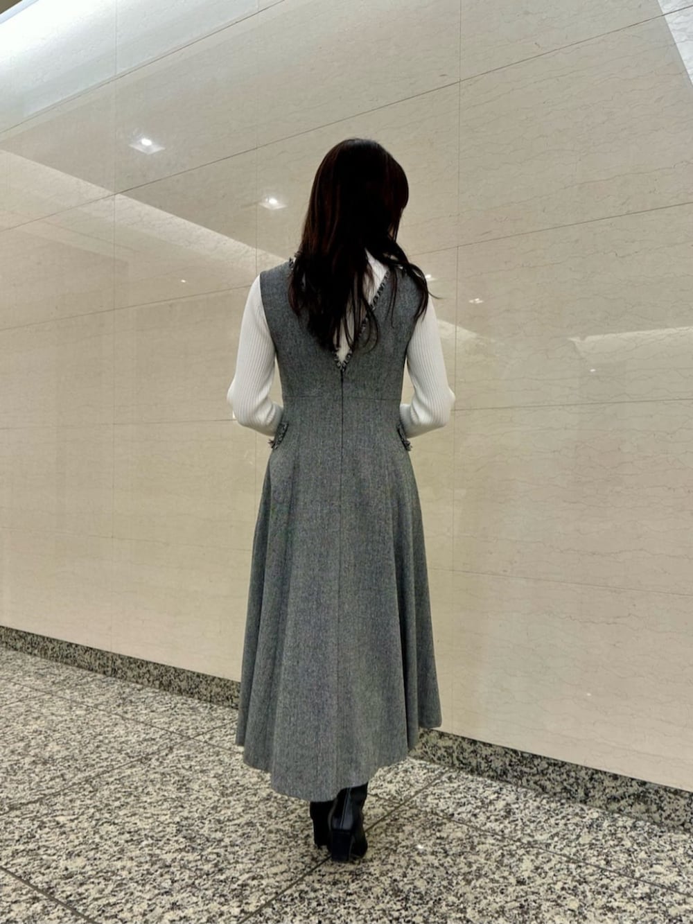 ブラック系のブーツ、ブルー系のノーカラーコート、ホワイト系のニット/セーターを着用したレディースの冬コーディネートの5枚目の写真