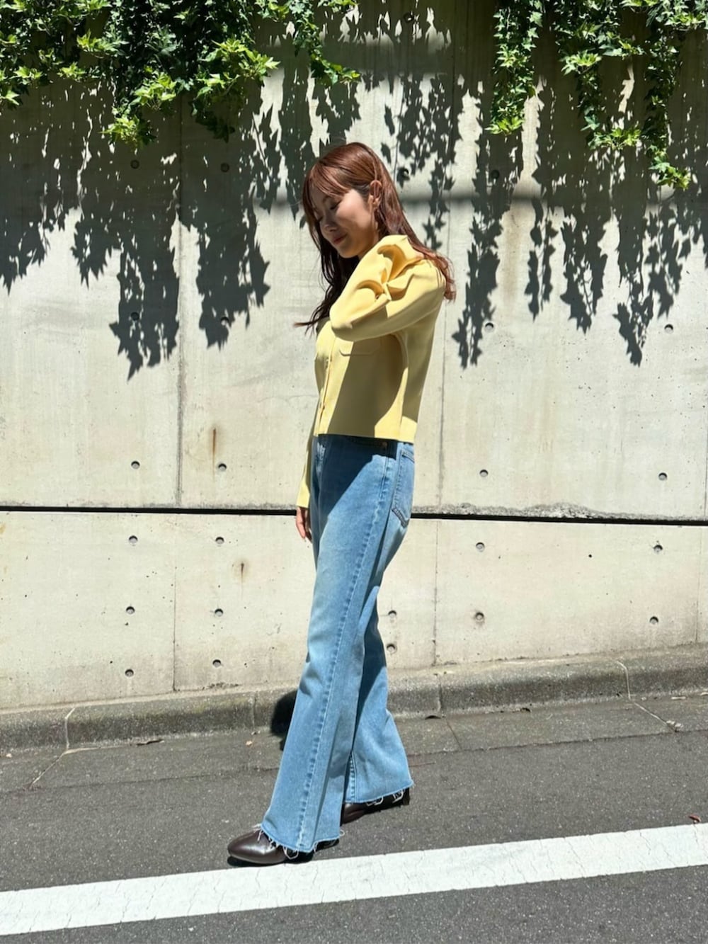 ブラウン系のブーツ、イエロー系のカーディガン/ボレロ、ブルー系のデニムパンツを着用したレディースの秋コーディネートの2枚目の写真