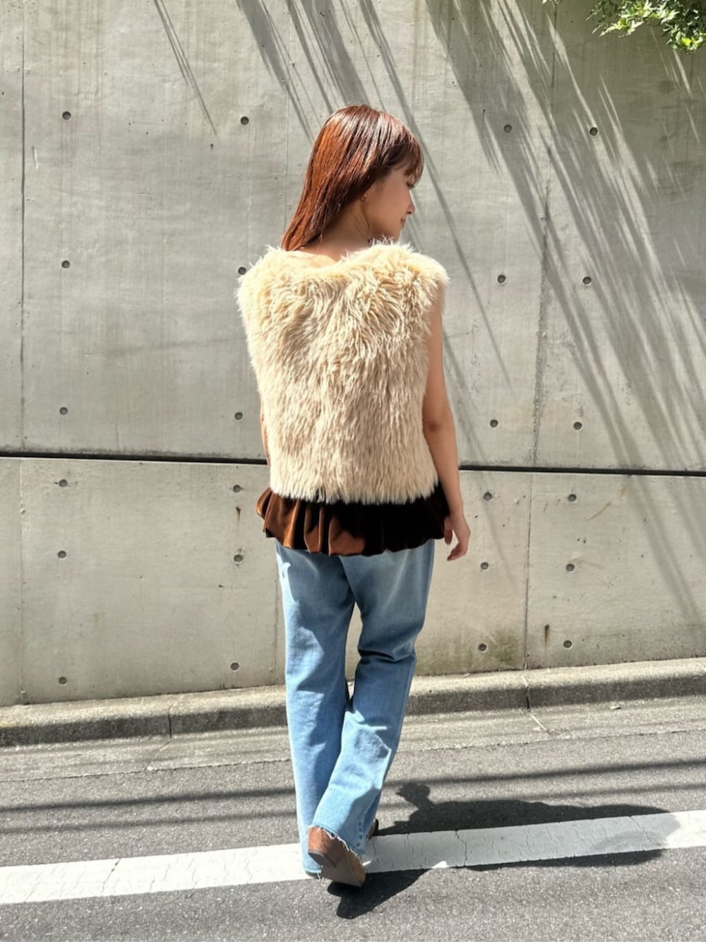 ベージュ系のベスト、ブラウン系のキャミソール、ブルー系のデニムパンツを着用したレディースの秋コーディネートの3枚目の写真