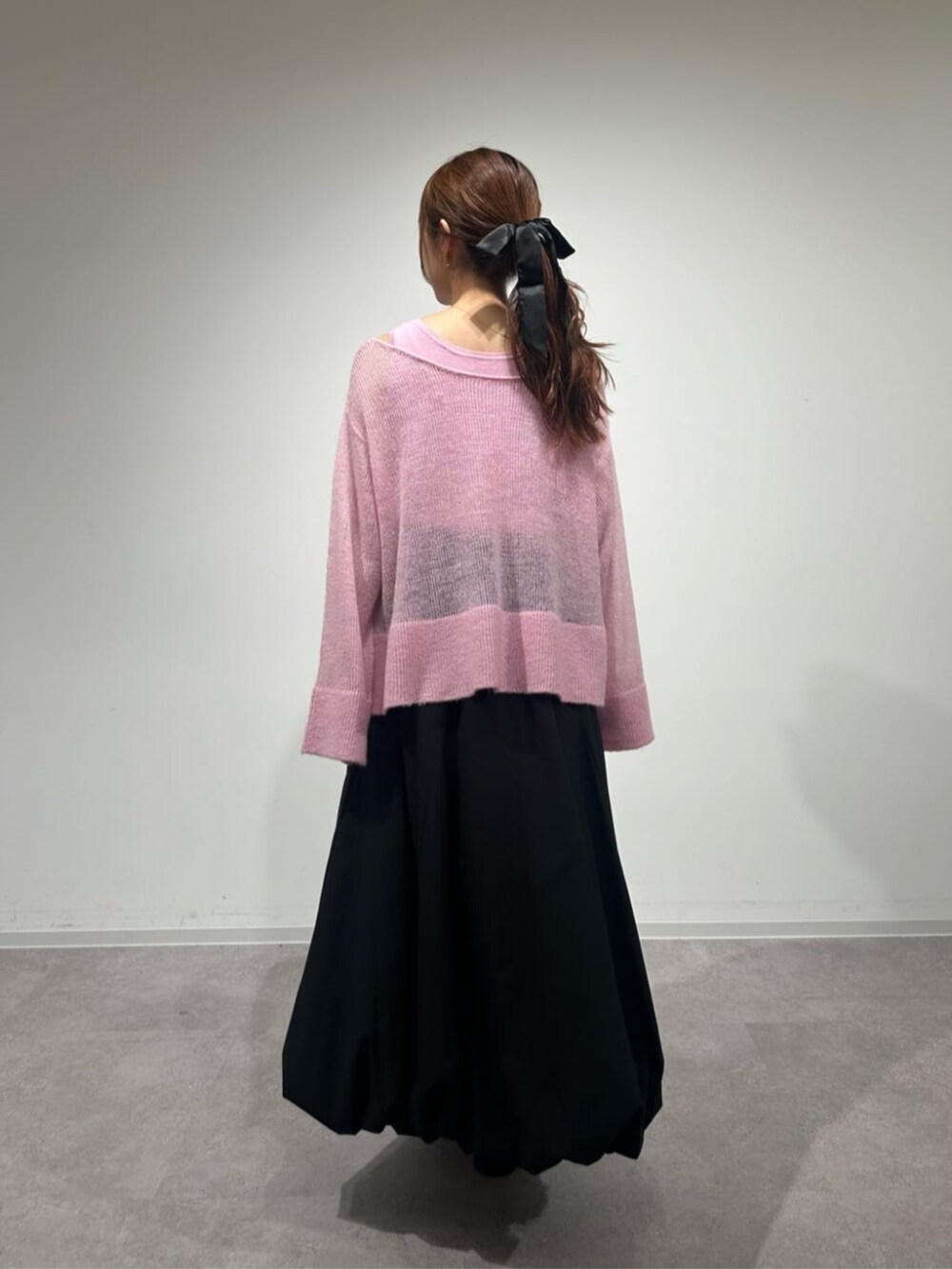 ピンク系のニット/セーター、ブラック系のスカート、ブラック系のブーツを着用したレディースの秋コーディネートの3枚目の写真