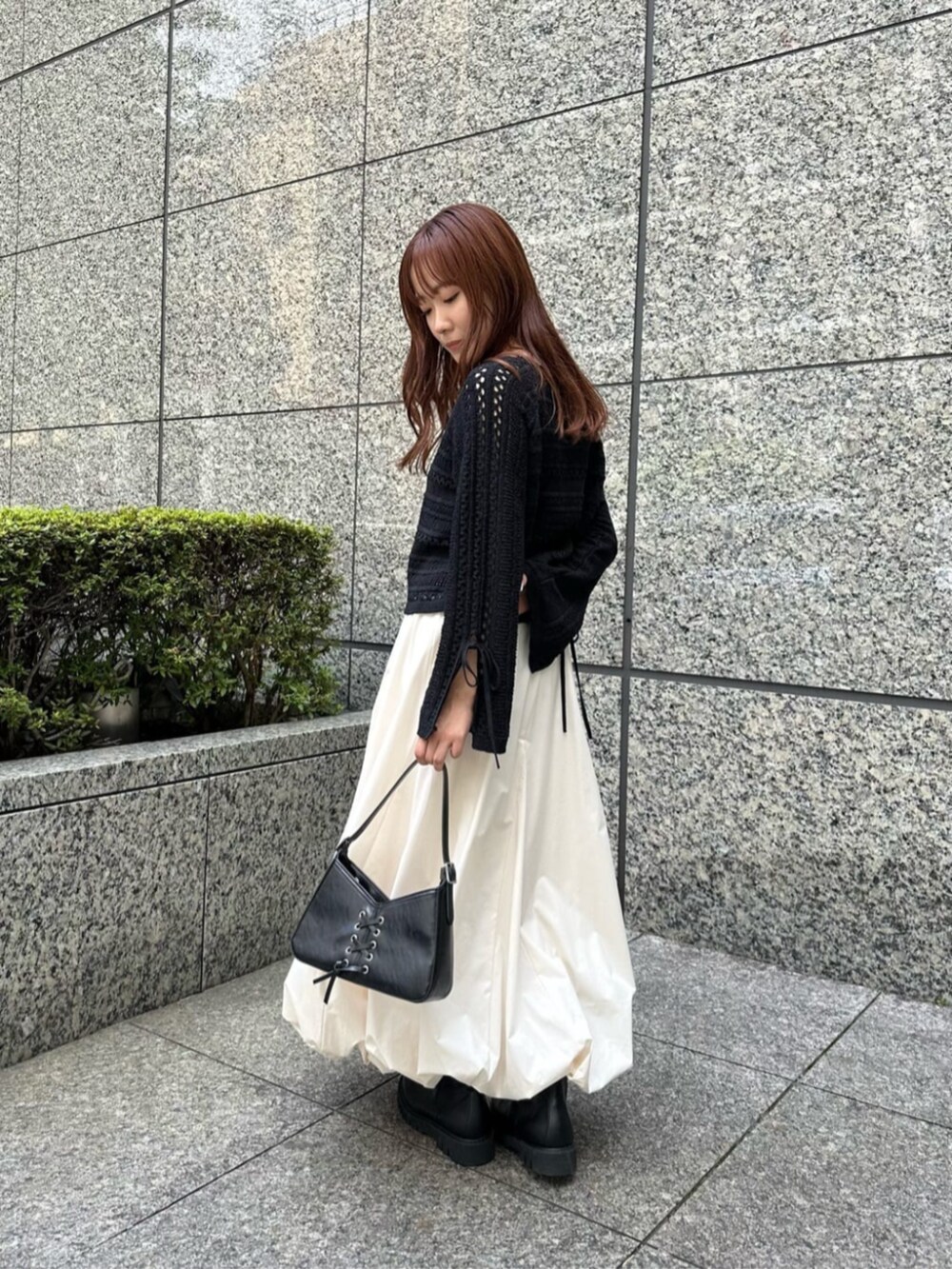 ブラック系のショルダーバッグ、ブラック系のブーツ、ホワイト系のスカートを着用したレディースの秋コーディネートの2枚目の写真