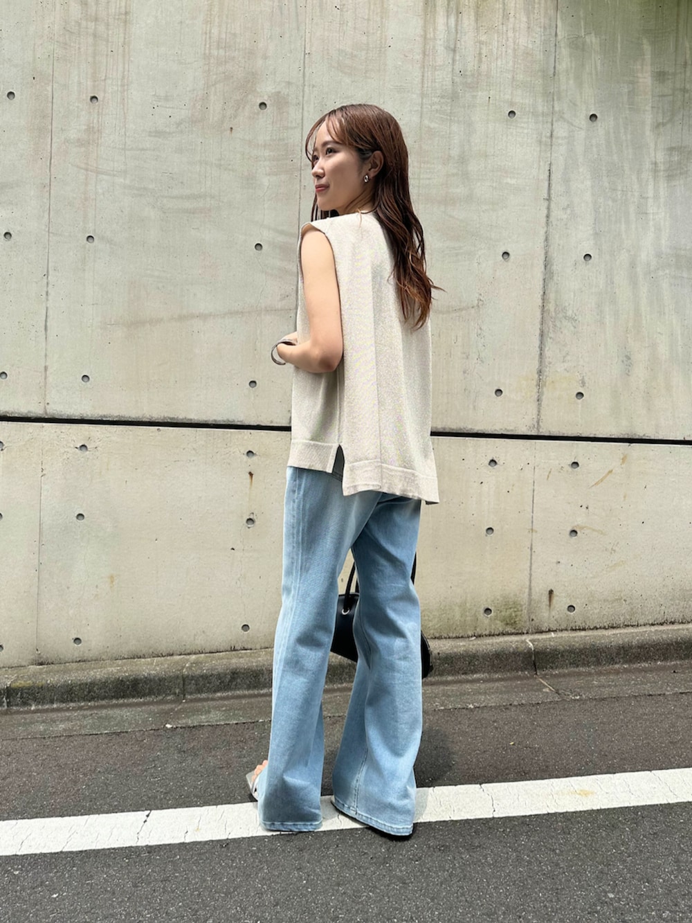 シルバー系のサンダル、ブラック系のボストンバッグ、ホワイト系のベストを着用したレディースの夏コーディネートの3枚目の写真