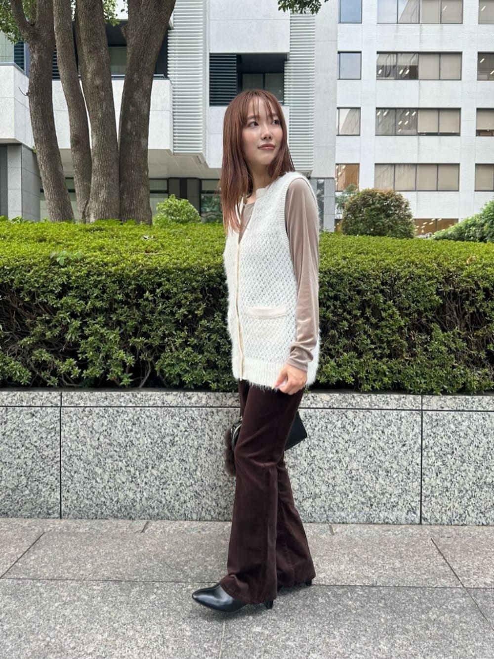 ブラック系のブーツ、ホワイト系のベスト、ベージュ系のTシャツ/カットソーを着用したレディースの秋コーディネートの2枚目の写真