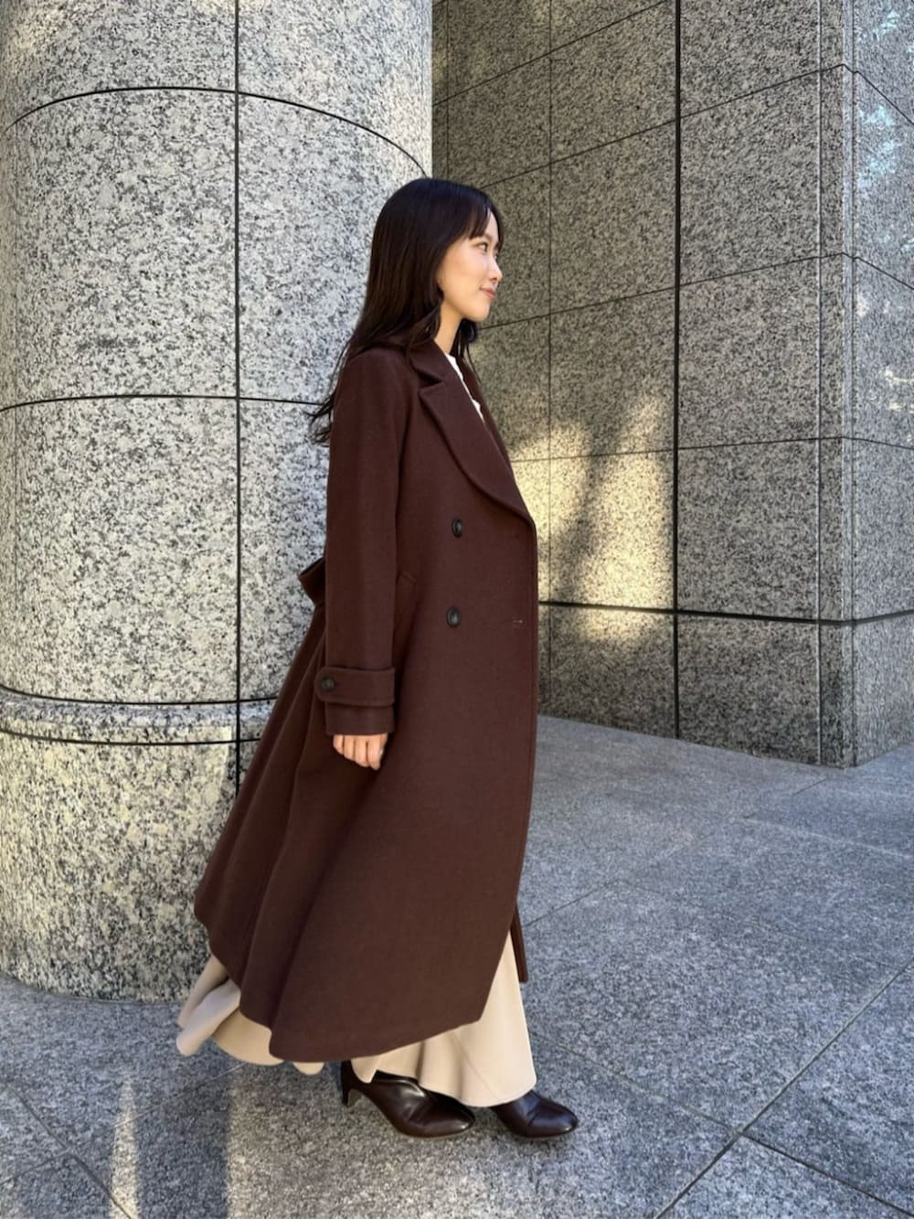 ブラウン系のブーツ、ブラウン系のチェスターコート、ホワイト系のニット/セーターを着用したレディースの冬コーディネートの2枚目の写真