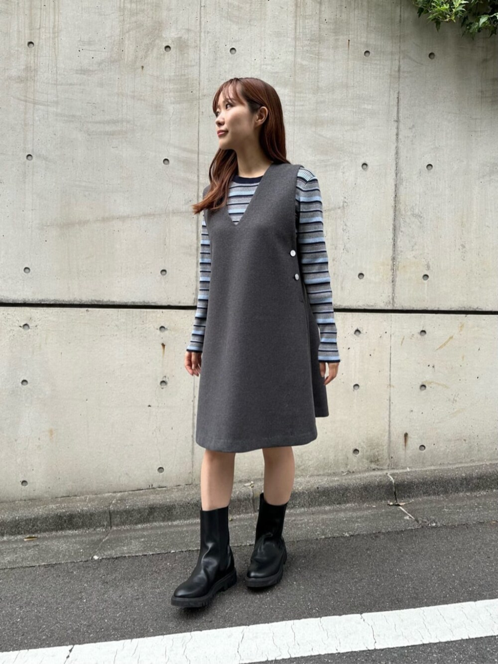 ブラック系のブーツ、グレー系のニット/セーター、グレー系のジャンパースカートを着用したレディースの秋コーディネートの4枚目の写真