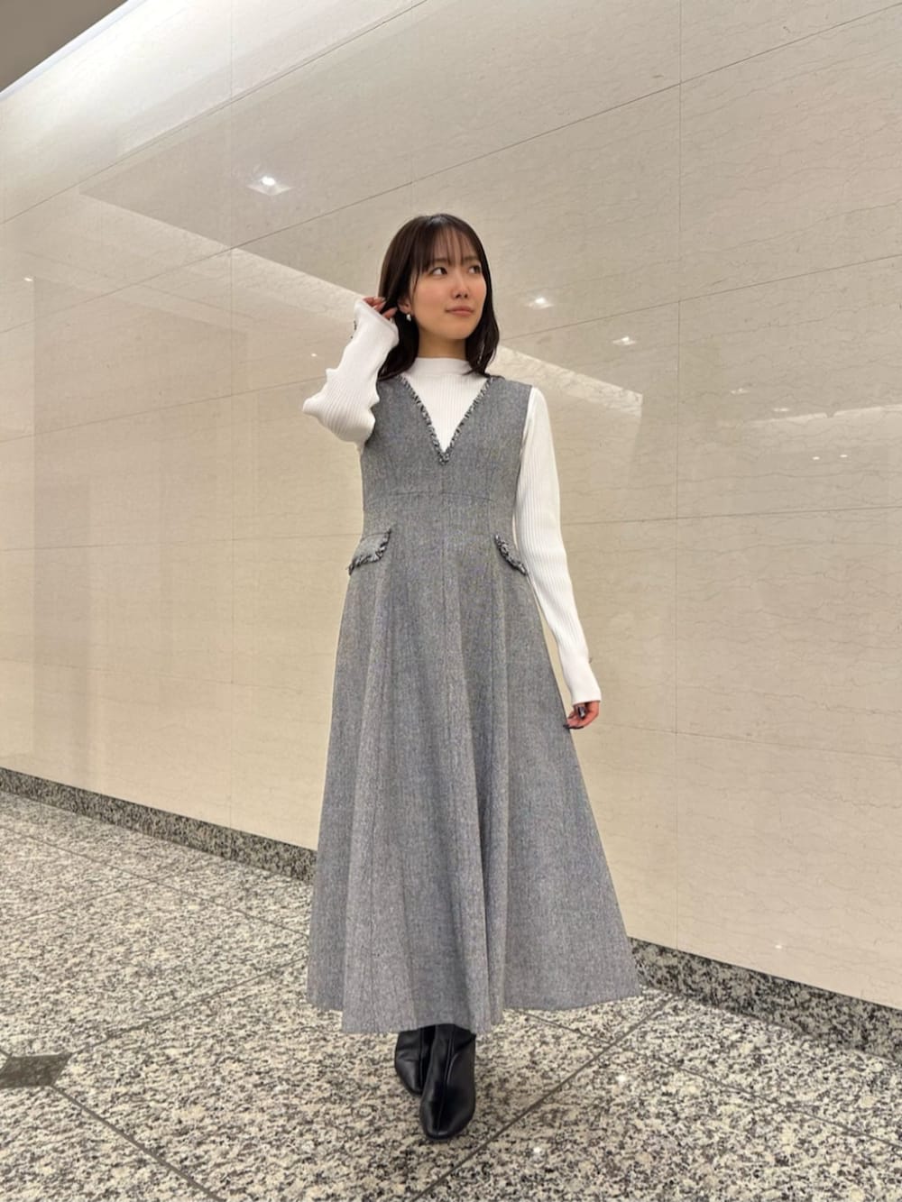 ブラック系のブーツ、ブルー系のノーカラーコート、ホワイト系のニット/セーターを着用したレディースの冬コーディネートの4枚目の写真