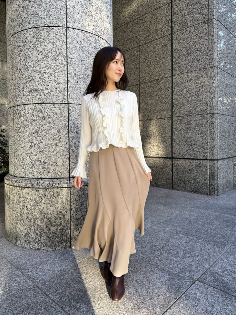 ブラウン系のブーツ、ブラウン系のチェスターコート、ホワイト系のニット/セーターを着用したレディースの冬コーディネートの4枚目の写真