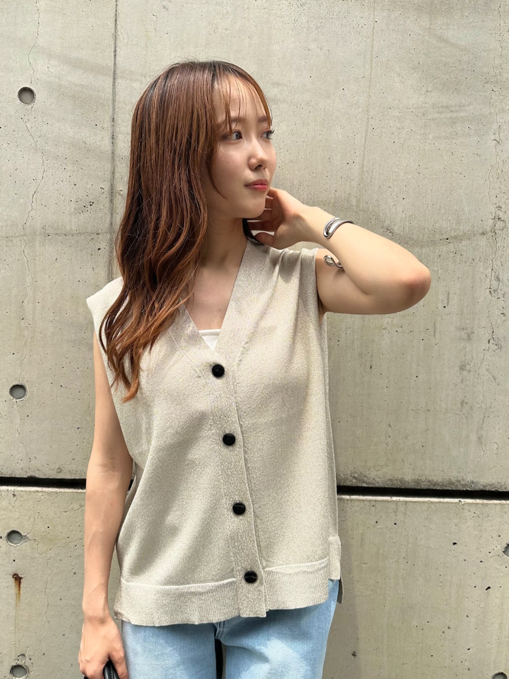 シルバー系のサンダル、ブラック系のボストンバッグ、ホワイト系のベストを着用したレディースの夏コーディネートの4枚目の写真