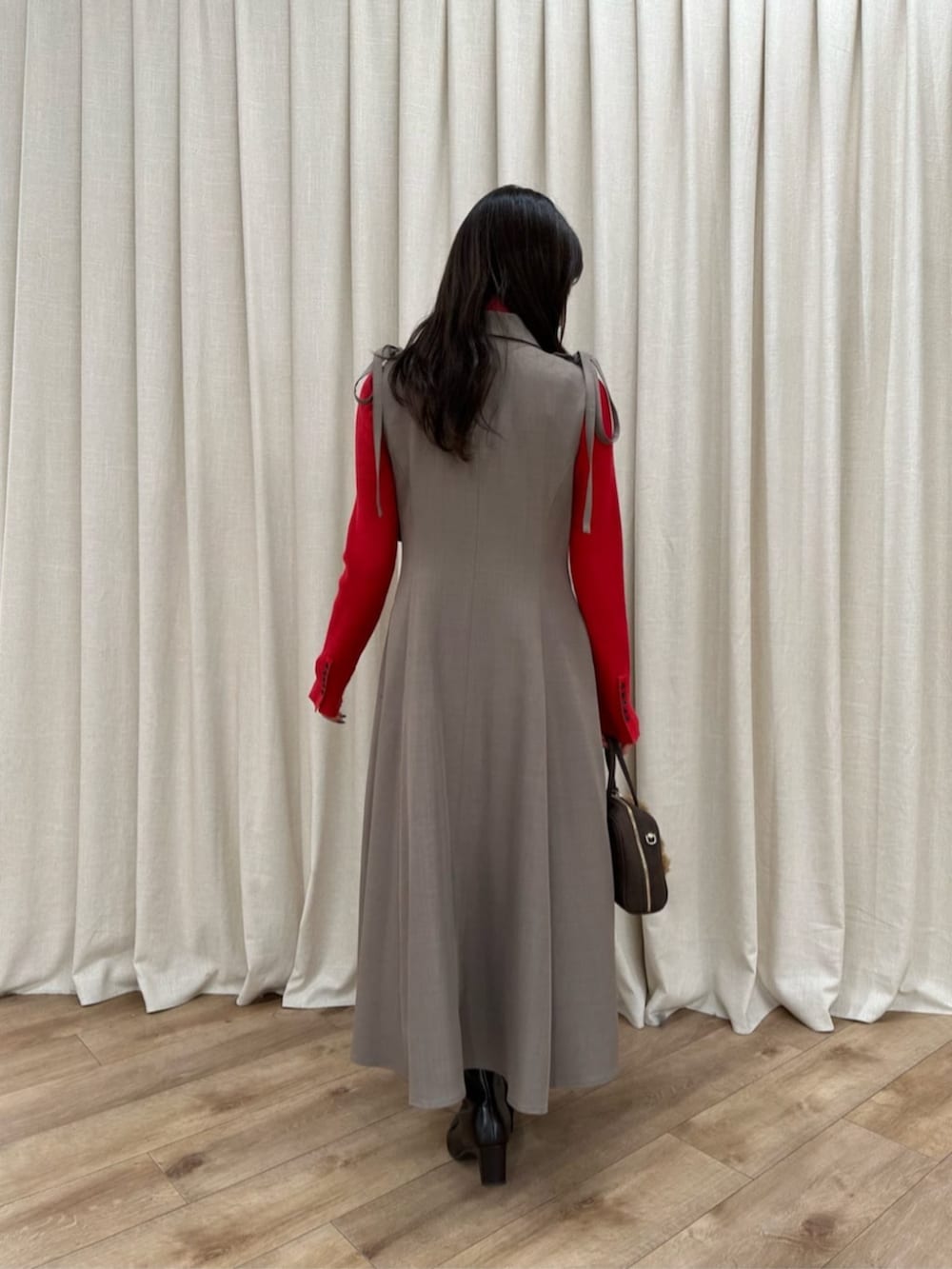 ブラック系のボストンバッグ、レッド系のニット/セーター、ベージュ系のジャンパースカートを着用したレディースの冬コーディネートの3枚目の写真