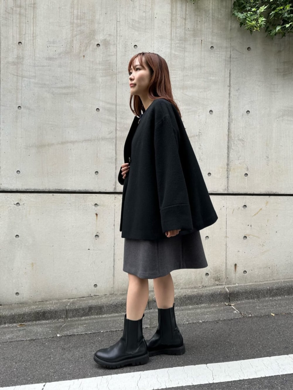 ブラック系のブーツ、グレー系のニット/セーター、グレー系のジャンパースカートを着用したレディースの秋コーディネートの2枚目の写真