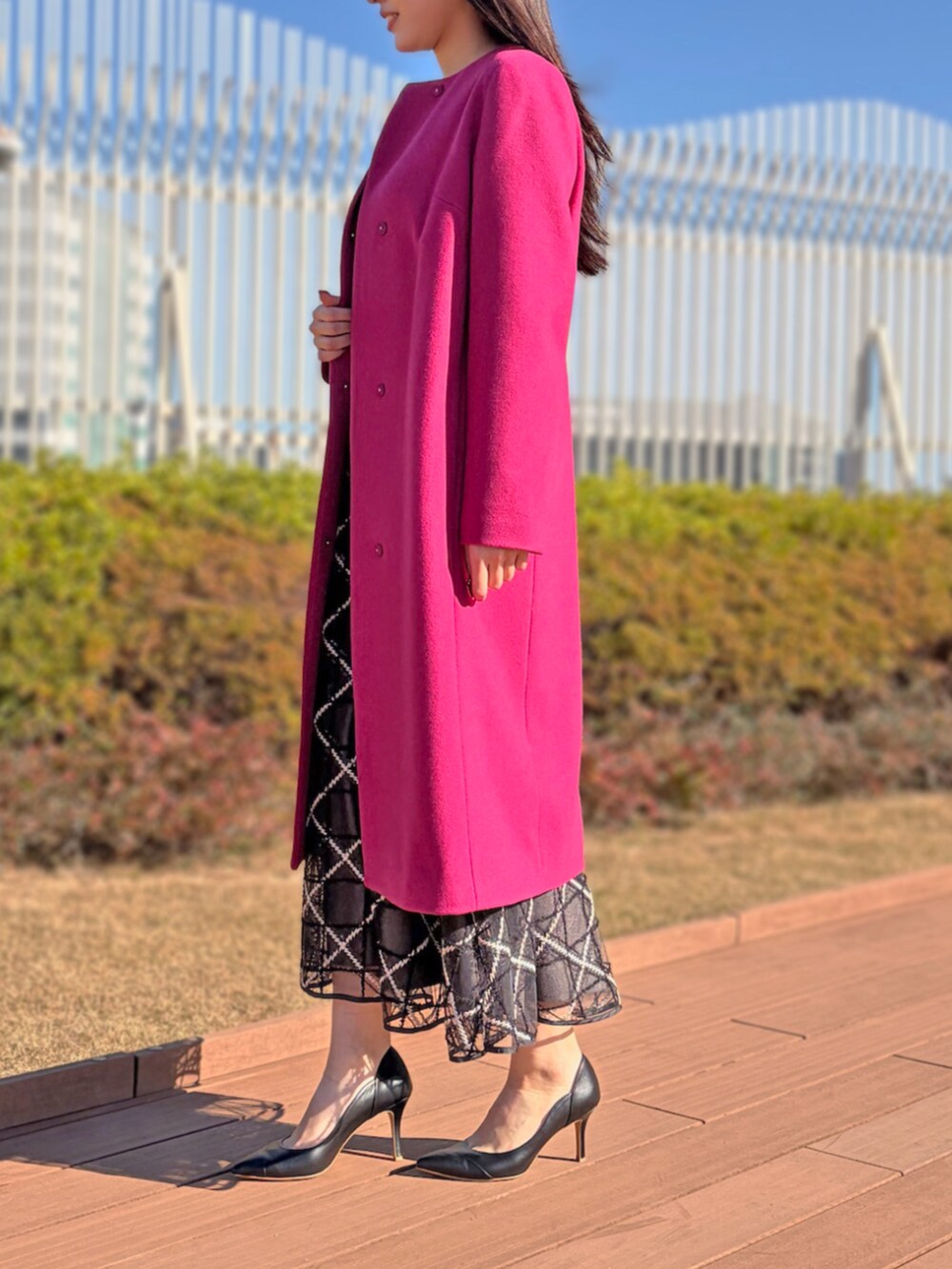 グレー系のスカート、ホワイト系のノーカラーコート、ホワイト系のニット/セーターを着用したレディースの冬コーディネートの2枚目の写真