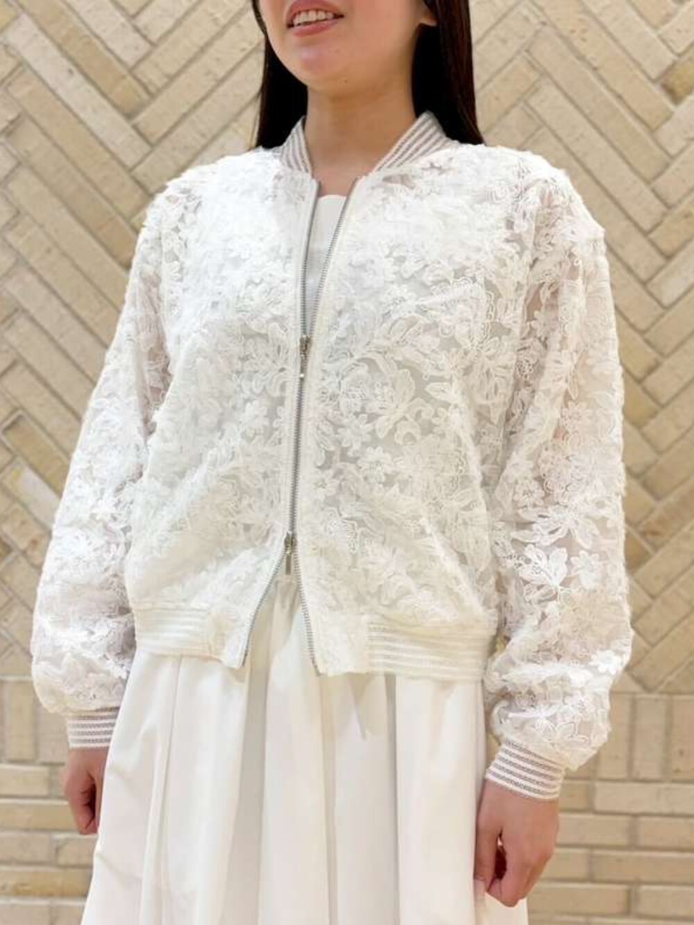 ホワイト系のスカート、ホワイト系のブルゾンを着用したレディースの春コーディネートの2枚目の写真