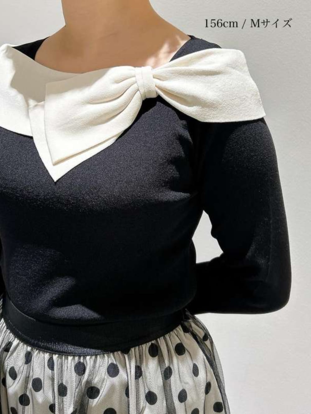 ホワイト系のスカート、ブラック系のニット/セーターを着用したレディースの春コーディネートの2枚目の写真