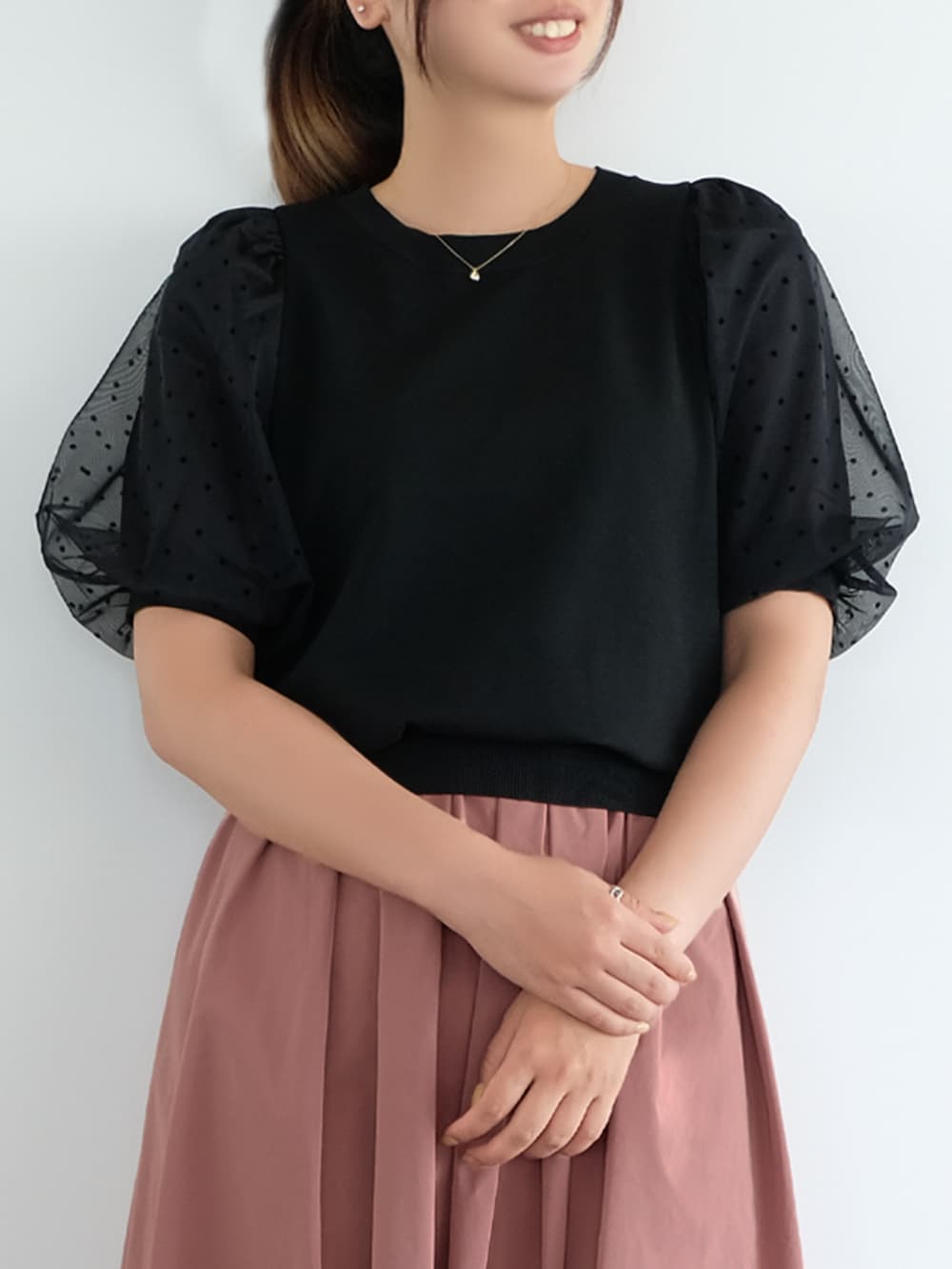 ブラック系のニット/セーター、ピンク系のスカートを着用したレディースの秋コーディネートの2枚目の写真