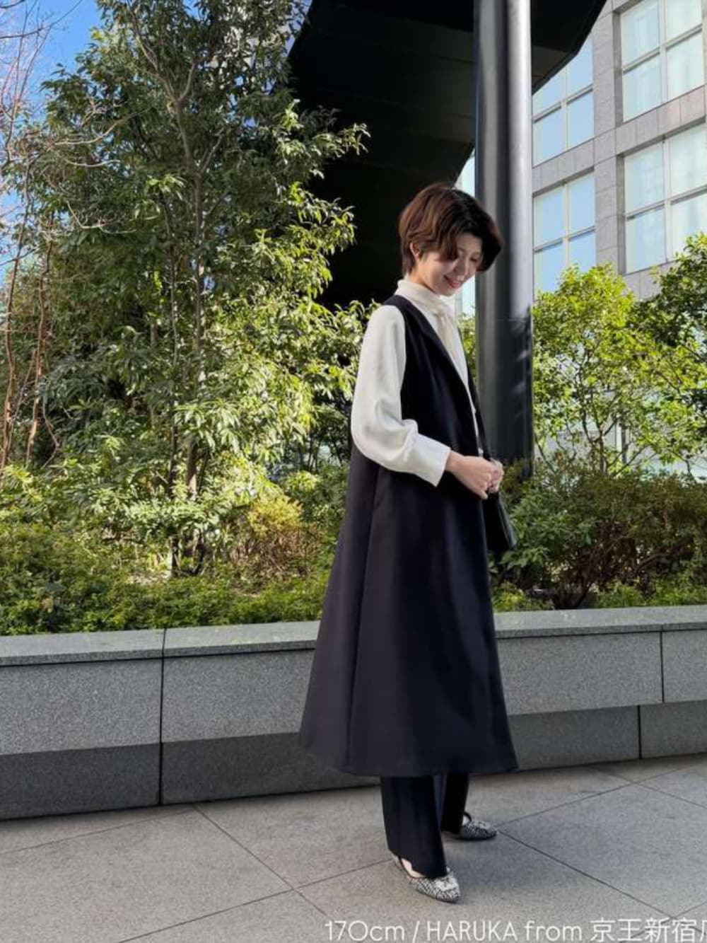 ブラック系のジャンパースカート、ホワイト系のシャツ/ブラウス、ブルー系のスラックスを着用したレディースの冬コーディネートの2枚目の写真