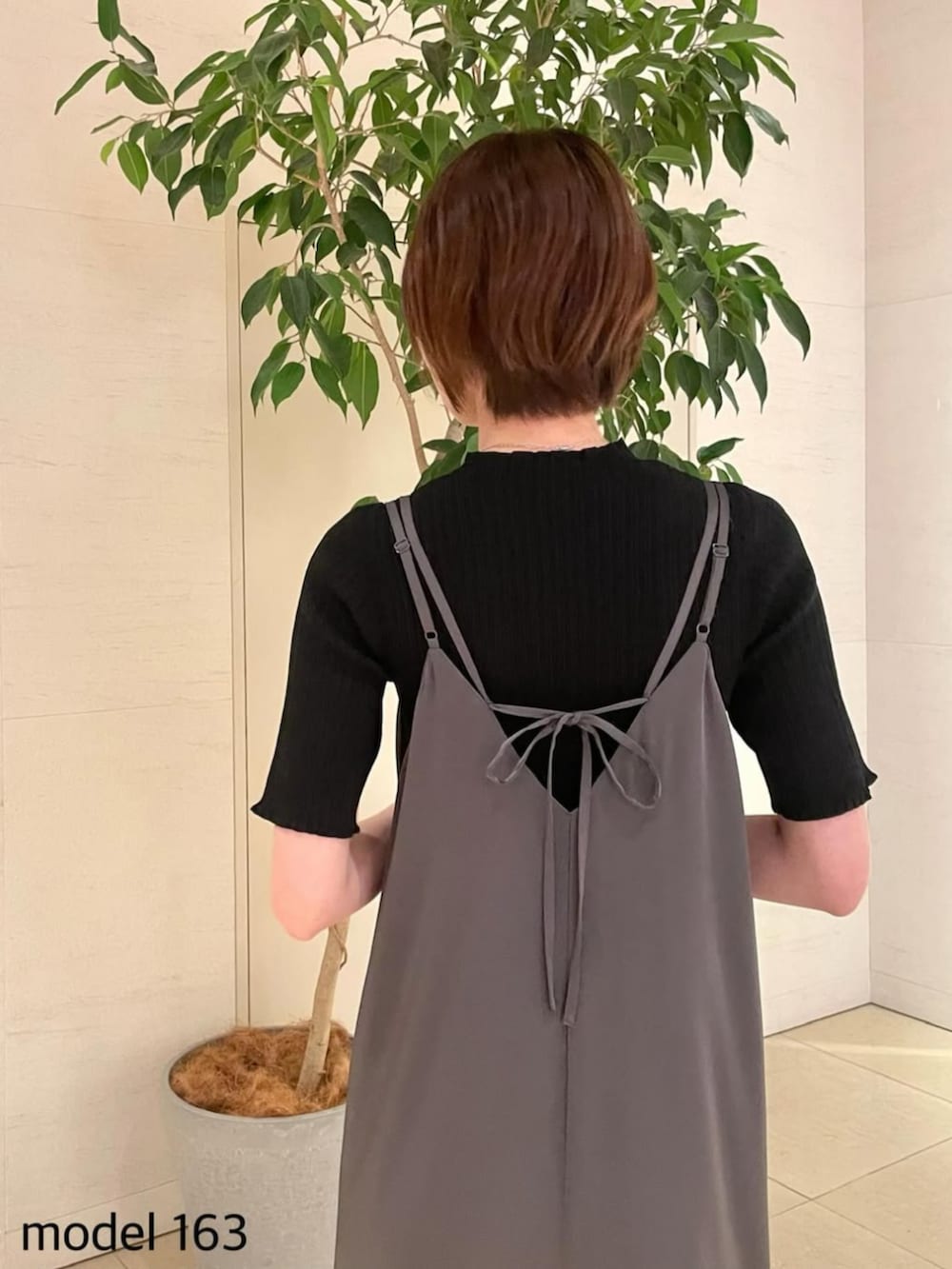 ブラック系のニット/セーター、グレー系のジャンパースカートを着用したレディースの夏コーディネートの2枚目の写真