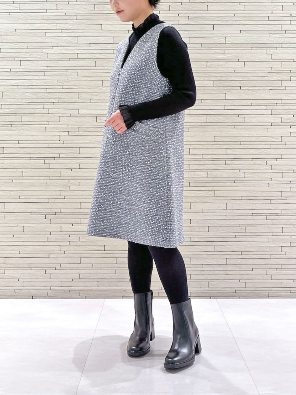 グレー系のジャンパースカート、ブラック系のニット/セーターを着用したレディースの冬コーディネートの2枚目の写真