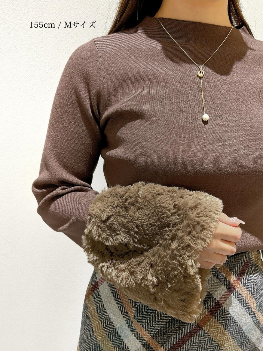 ブラウン系のニット/セーター、ブルー系のスカートを着用したレディースの秋コーディネートの2枚目の写真