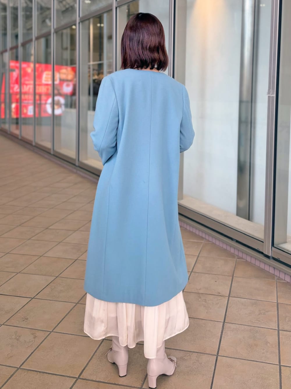 ホワイト系のノーカラーコートを着用したレディースの冬コーディネートの3枚目の写真