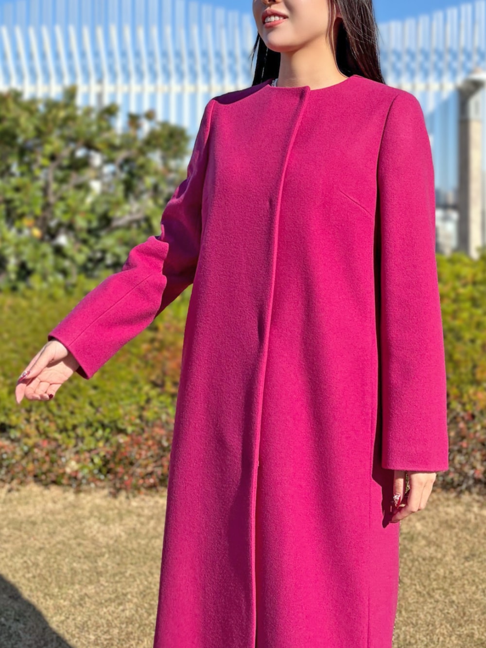 グレー系のスカート、ホワイト系のノーカラーコート、ホワイト系のニット/セーターを着用したレディースの冬コーディネートの3枚目の写真