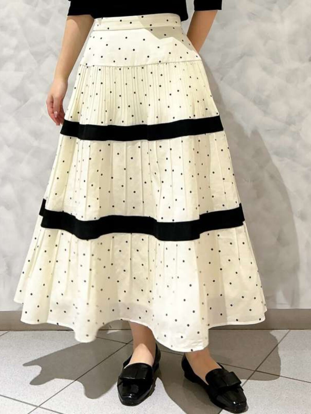 ホワイト系のスカート、ブラック系のTシャツ/カットソーを着用したレディースの春コーディネートの2枚目の写真