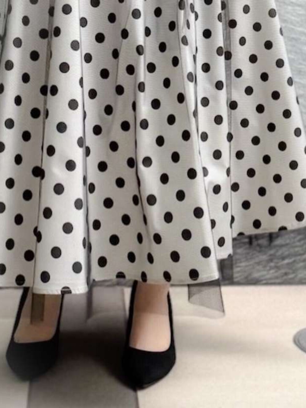 ブラック系のニット/セーター、ホワイト系のスカートを着用したレディースの春コーディネートの3枚目の写真