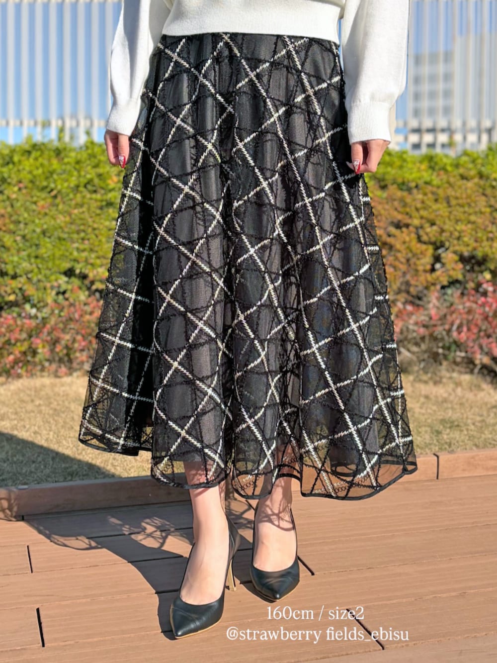 グレー系のスカート、ホワイト系のニット/セーターを着用したレディースの冬コーディネートの3枚目の写真