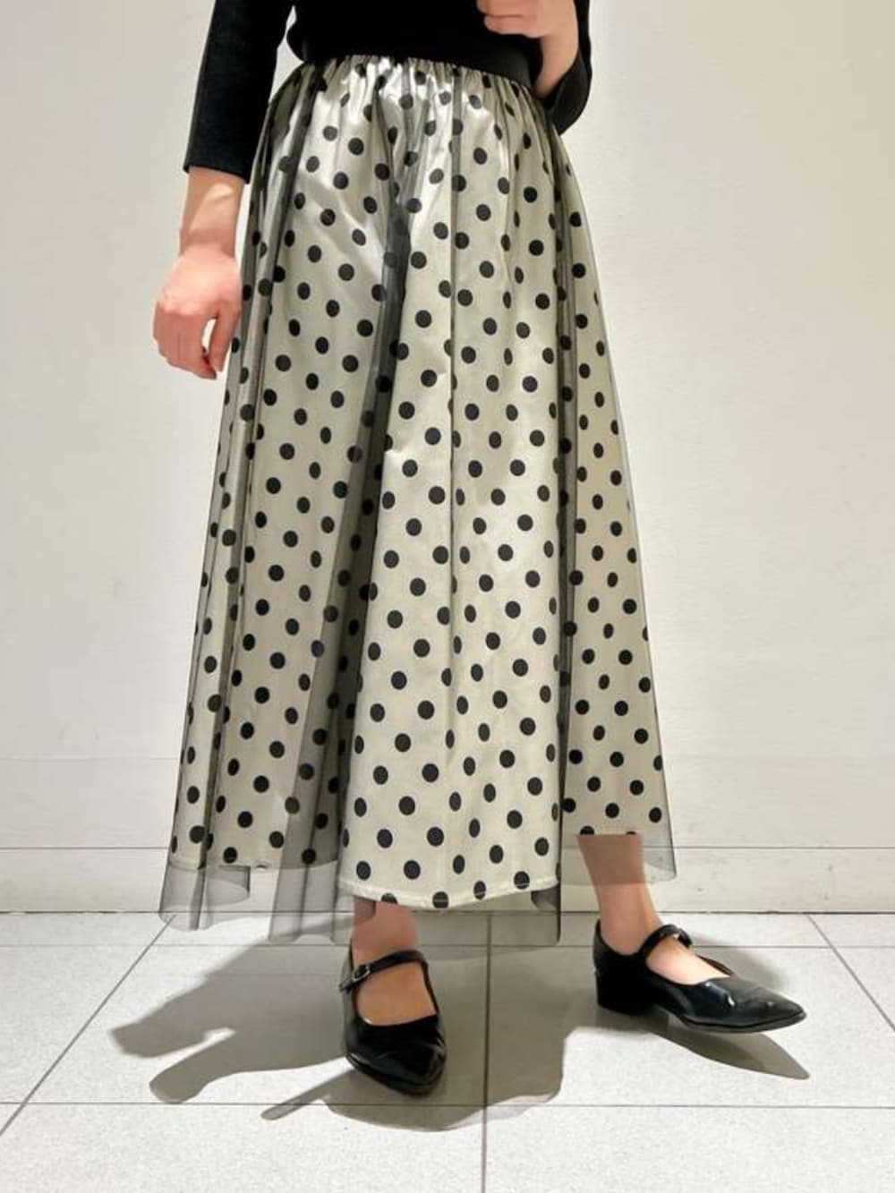 ホワイト系のスカート、ブラック系のニット/セーターを着用したレディースの春コーディネートの3枚目の写真