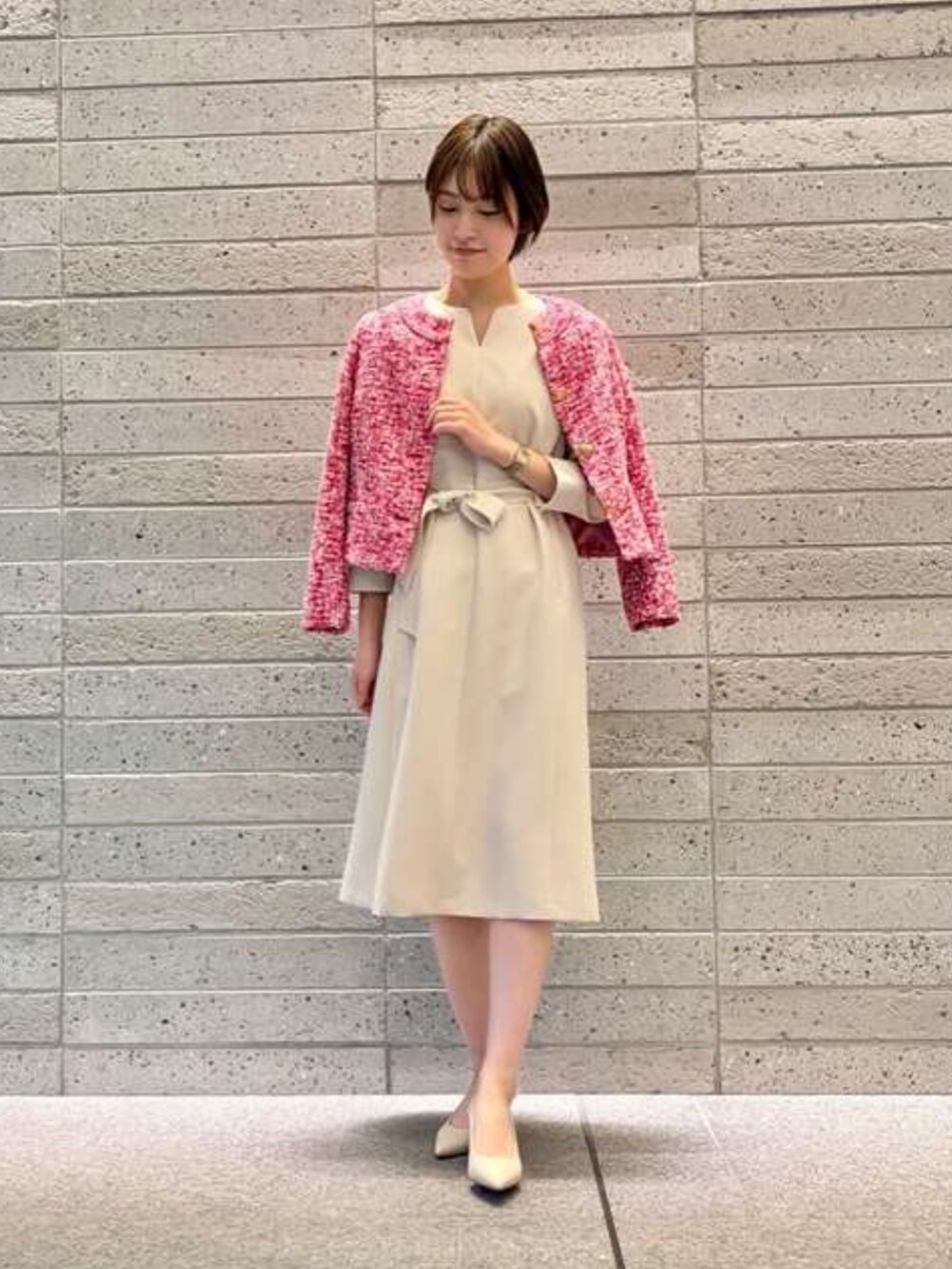 ピンク系のノーカラージャケット、ベージュ系のワンピースを着用したレディースの冬コーディネートの2枚目の写真