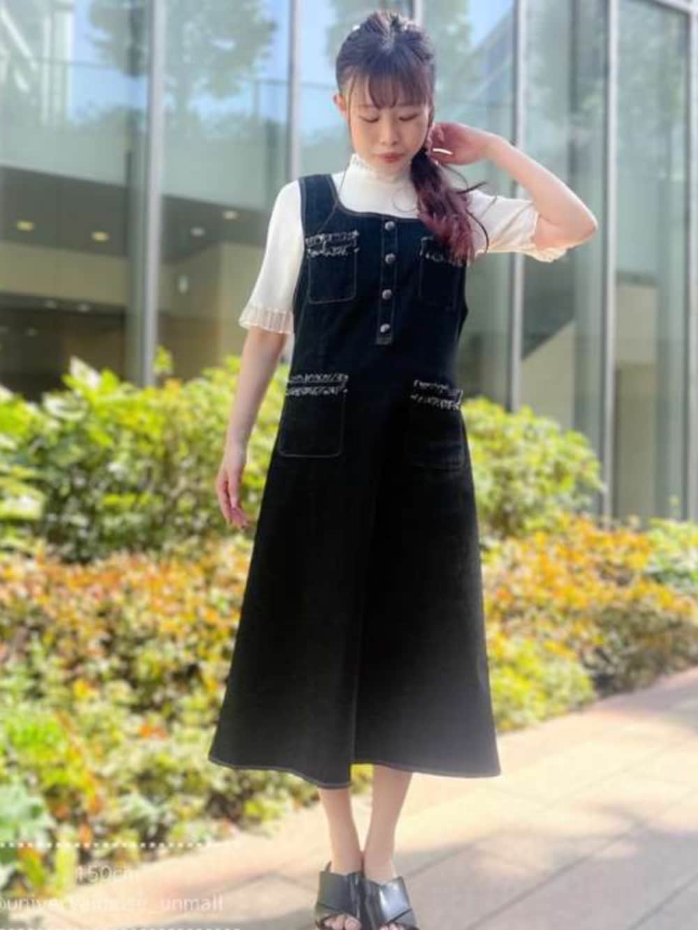 ブルー系のジャンパースカート、ホワイト系のニット/セーターを着用したレディースの春コーディネートの2枚目の写真