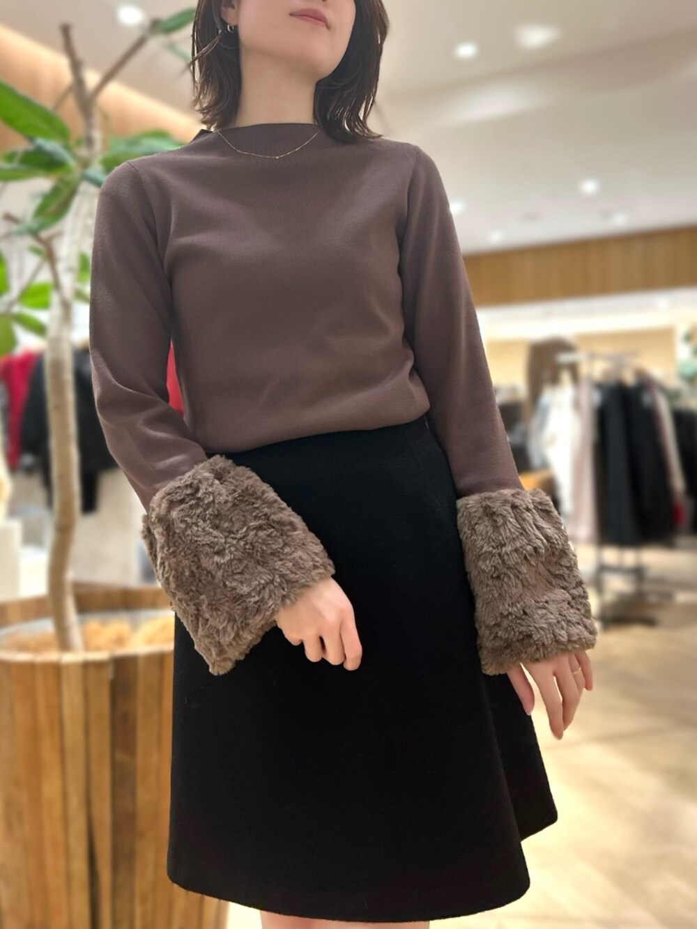 ブラウン系のニット/セーター、ブラック系のスカートを着用したレディースの秋コーディネートの2枚目の写真