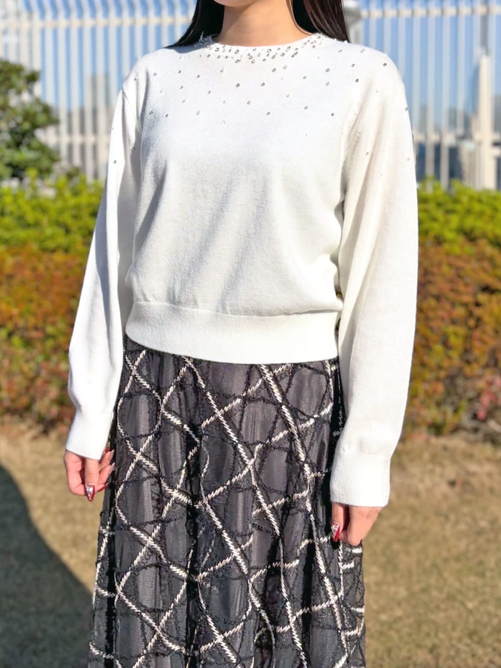 グレー系のスカート、ホワイト系のニット/セーターを着用したレディースの冬コーディネートの2枚目の写真