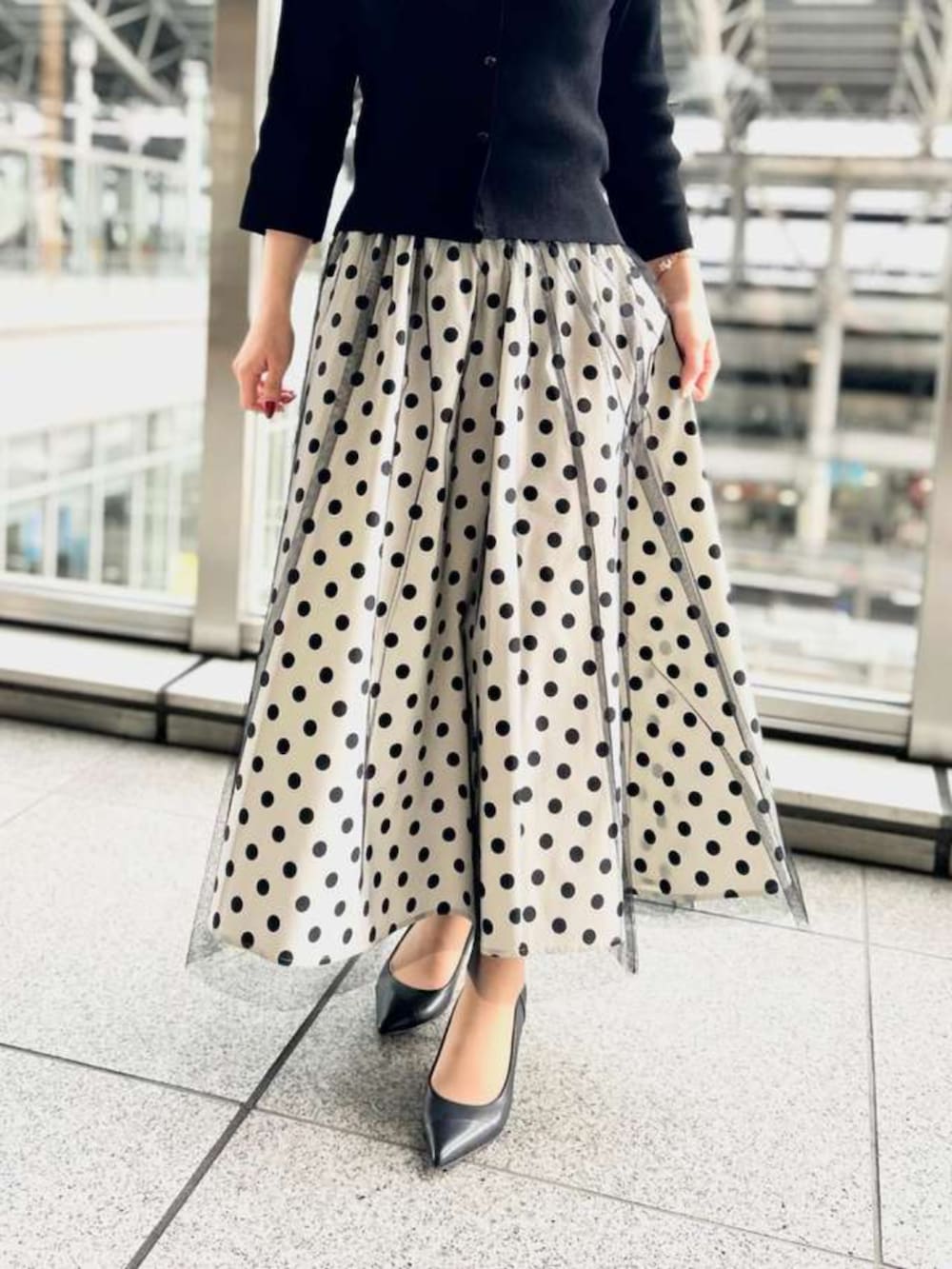 ホワイト系のスカート、ブラック系のニット/セーターを着用したレディースの春コーディネートの3枚目の写真