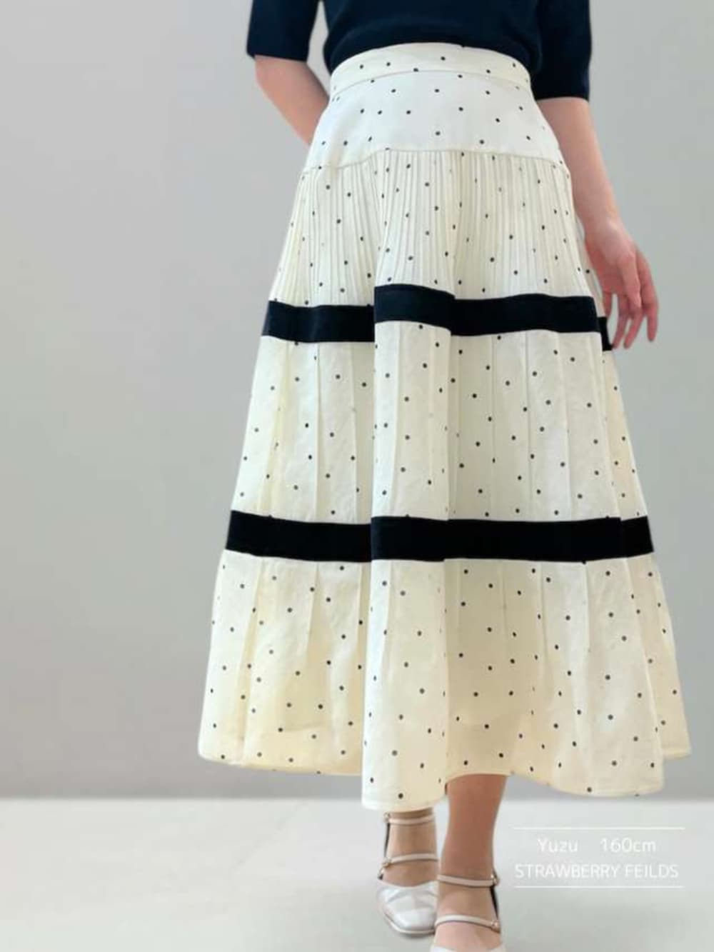 ホワイト系のスカート、ブラック系のニット/セーターを着用したレディースの春コーディネートの2枚目の写真