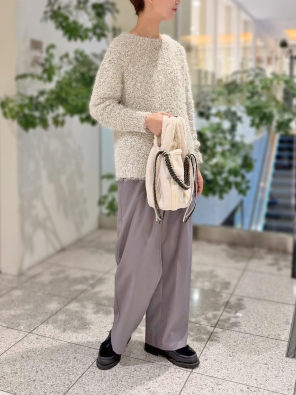 グレー系のスラックス、ホワイト系のニット/セーターを着用したレディースの冬コーディネートの2枚目の写真