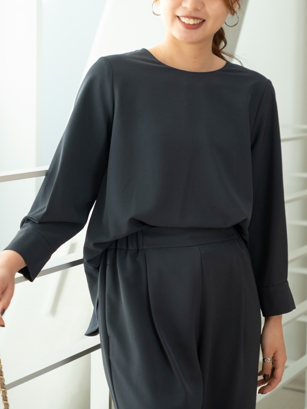 ブラック系のスラックス、ブルー系のビジネスシャツを着用したレディースの冬コーディネートの2枚目の写真