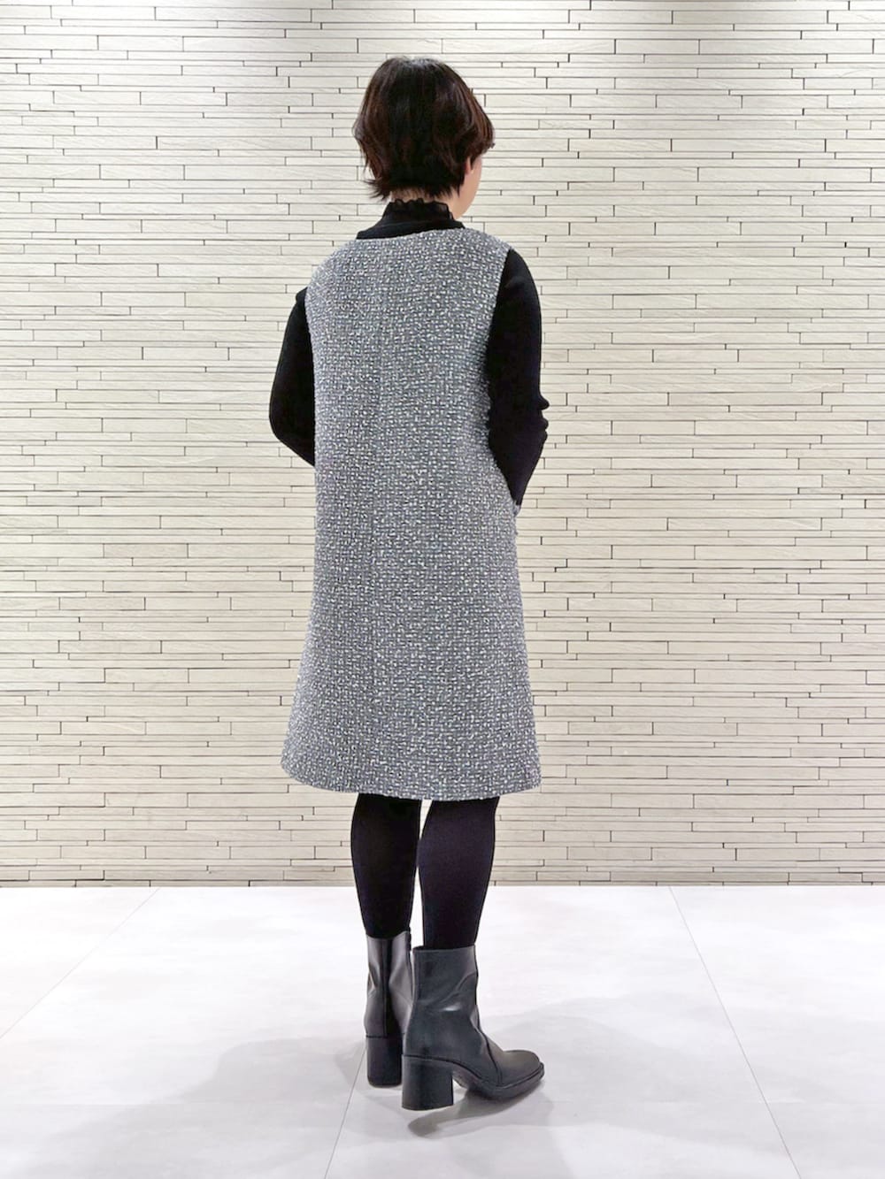 グレー系のジャンパースカート、ブラック系のニット/セーターを着用したレディースの冬コーディネートの3枚目の写真