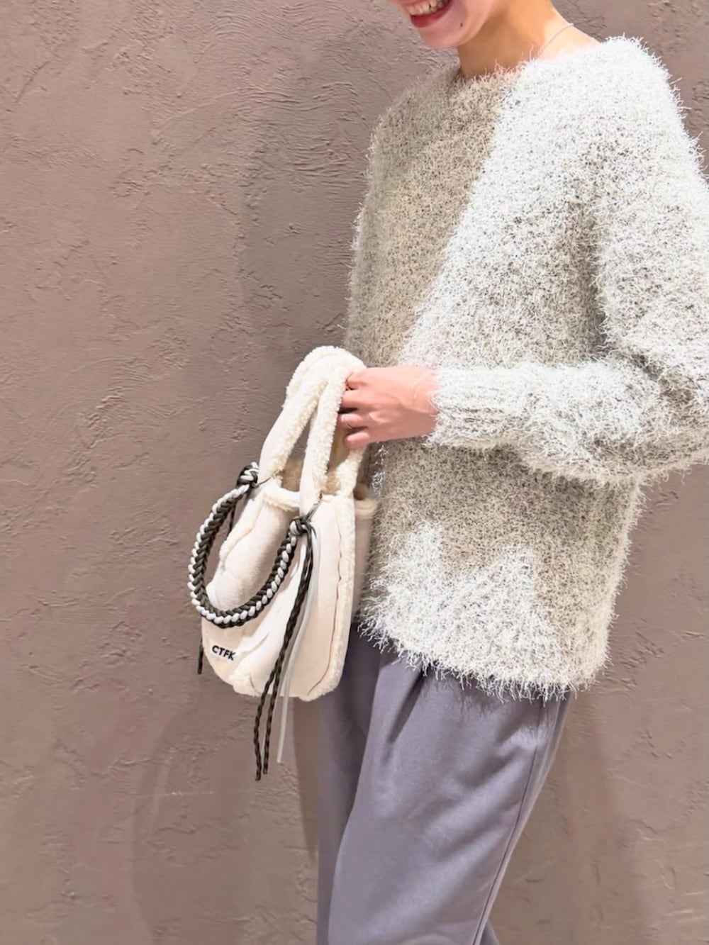 グレー系のスラックス、ホワイト系のニット/セーターを着用したレディースの冬コーディネートの3枚目の写真