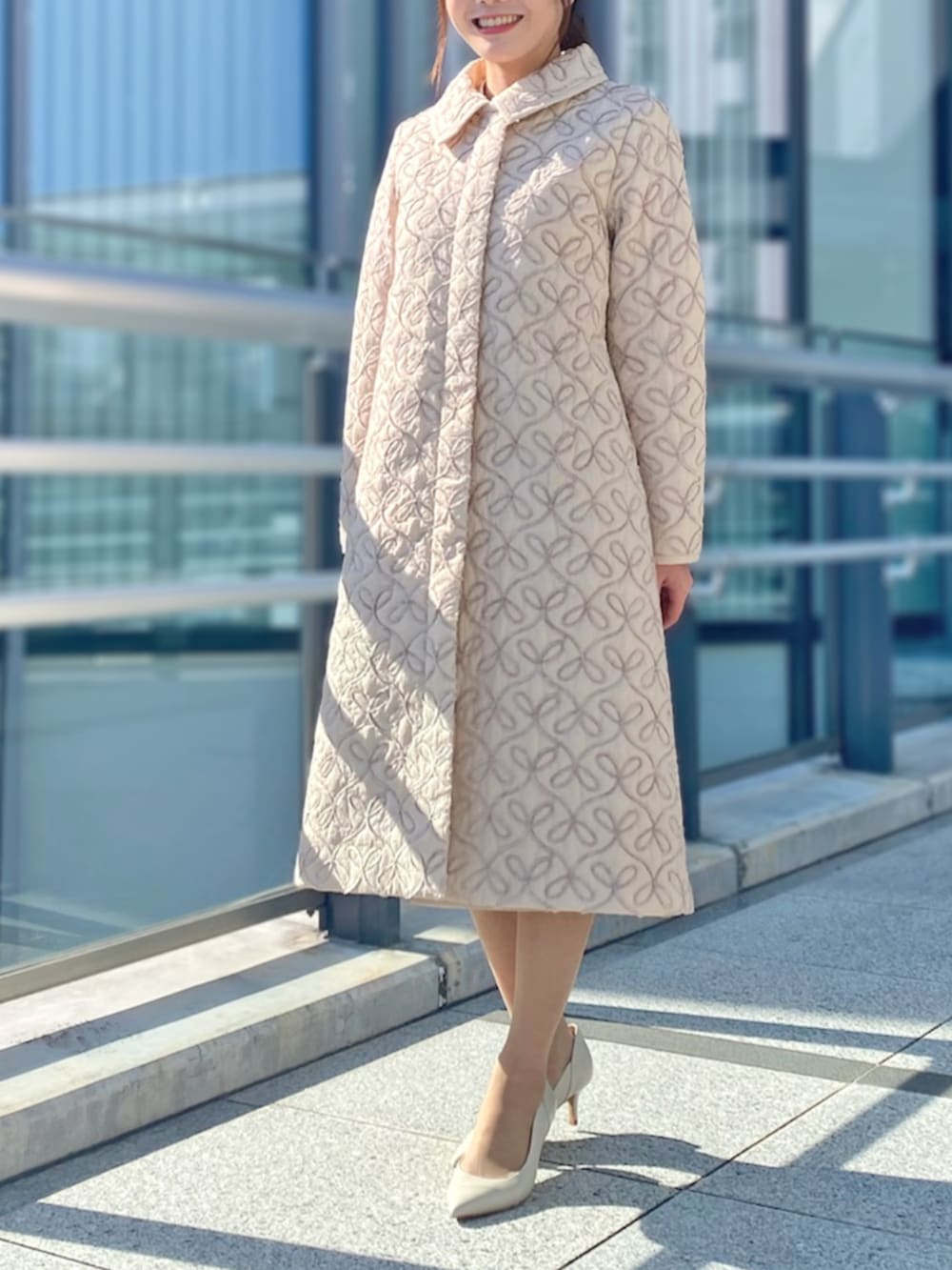 ホワイト系のスカート、ピンク系のステンカラーコート、ホワイト系のニット/セーターを着用したレディースの秋コーディネートの3枚目の写真