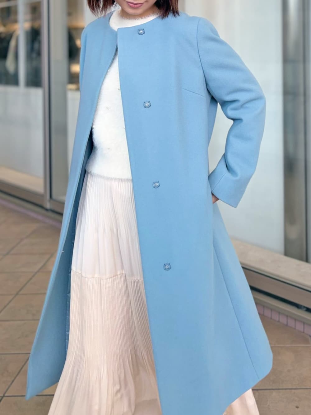 ホワイト系のノーカラーコートを着用したレディースの冬コーディネートの2枚目の写真