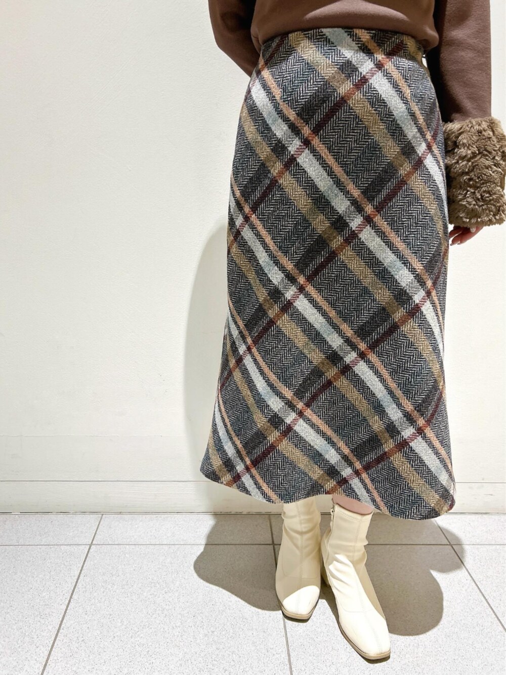 ブラウン系のニット/セーター、ブルー系のスカートを着用したレディースの秋コーディネートの3枚目の写真